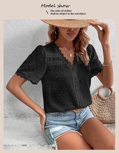 Close-up of textured black V-neck shirt with delicate lace trim and dotted fabric details