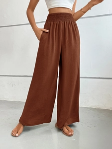 Detail of high-waist elastic waistband and side pocket on brown wide-leg trousers