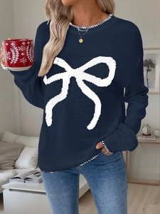 Dettaglio del maglione in maglia blu scuro con fiocco bianco e cuciture a contrasto