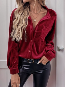 Detail of burgundy velvet shirt featuring a classic collar and smooth metallic buttons