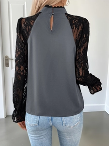 Detail of the high collar lace trim and button back cutout on a long sleeve grey top
