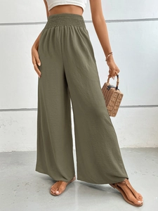 Detail of wide elastic waistband and olive green textured fabric on wide-leg trousers