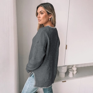 Detail of dark grey oversized knit sweater with white contrast blanket stitch and side slits