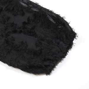 Detail of elegant black dress sleeve with intricate fringe textures and sheer mesh fabric