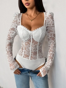 Détail du body blanc à manches longues en dentelle avec armatures et motifs floraux