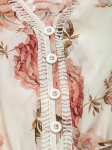 Détail de robe florale avec col en V, bordure en dentelle crochet et boutons blancs