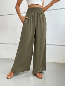 Detail of high-waisted olive wide-leg pants with elastic pleated waist and side pockets