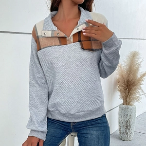 Detail of quilted grey sweatshirt with plaid patchwork neckline and metal snap buttons