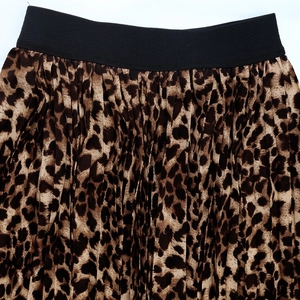 Close-up of leopard print pleated skirt showing black elastic waistband and fabric texture