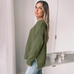 Detail of olive green knit sweater featuring white contrast stitching and side split hem
