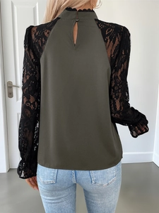 Detail of army green blouse featuring black lace sleeves and high collar with hollow design