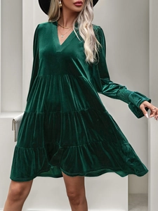 Detail of dark green velvet dress featuring elegant V-neck and ruffled tiered skirt design