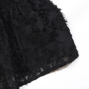 Close-up of black feather-textured jacquard fabric with elegant fringe detailing