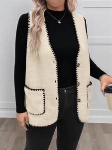 Dettaglio del gilet in pile beige con cuciture a contrasto nere e ampie tasche
