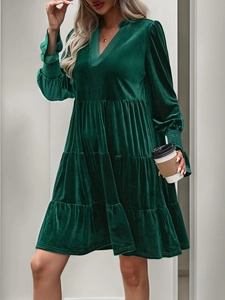 Close-up of V-neck dark green velvet dress with tiered skirt and smocked cuffs detail