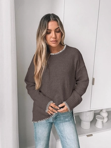 Detail of dark brown knit sweater with white contrast stitching and side slit hem