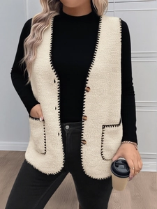 Dettaglio del gilet in pile beige con bordi a punto croce neri e bottoni tartarugati