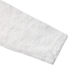 Gros plan sur les motifs de dentelle florale blanche et les détails ajourés des manches