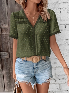Detail of V-neck dark green Swiss dot blouse with delicate lace embroidery and texture