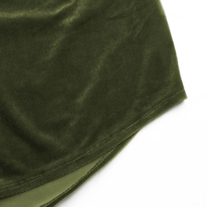 Detailed close-up of dark green velvet fabric texture and hem stitching on the shirt