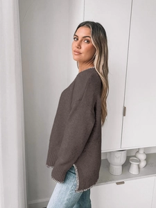 Detail view of oversized dark knit sweater featuring white whipstitch trim and side slits