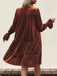 Detailed view of bronze velvet tiered dress showing elegant layered texture and long sleeves