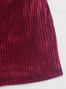 Détail macro du tissu en velours côtelé bordeaux avec une texture verticale fine