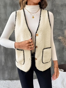 Dettaglio del gilet sherpa bianco con bordo a punto sopraggitto nero e bottoni dorati