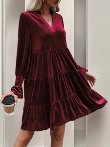 Detail view of burgundy velvet mini dress showing layered ruffle hem and V-neckline