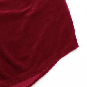 Detailed macro shot of dark red velvet fabric hem showing high-quality stitching and texture