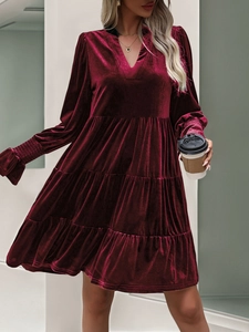 Detail of burgundy velvet dress featuring elegant V-neck and layered ruffle skirt texture