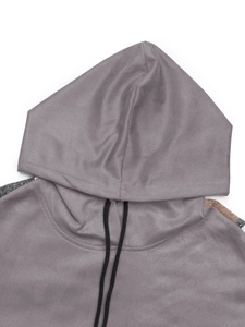 Détail du col d'un sweat à capuche avec cordons et empiècements à carreaux