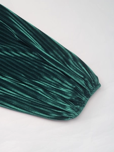 Détail de la manchette en velours plissé vert foncé avec une texture élégante