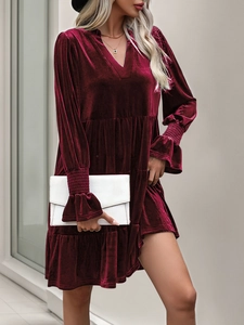 Detail of burgundy velvet dress showing V-neckline and layered ruffled hemline