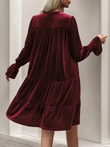 Detail view of tiered wine red velvet dress with ruffled hem and long sleeves