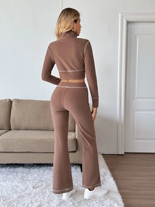 Detail eines braunen Sport-Sets mit Kontrastnähten und Schlaghose mit hoher Taille