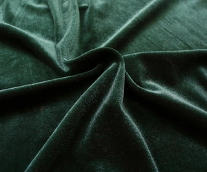 Detail shot of luxurious emerald green velvet fabric with soft folds and silk-like sheen