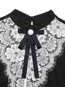 Detail of white floral lace collar with a pearl-encrusted bow on a black vintage dress