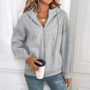 Detail of silver rhinestones and metal beads on a light grey hooded zip-up sweatshirt