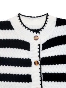 Detail of black and white striped knit cardigan with amber buttons and textured fabric