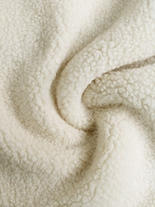 Dettaglio macro del tessuto in pile sherpa bianco con morbide fibre di lana