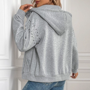 Detail view of light gray zip-up hoodie featuring rhinestone studs and ribbed cuffs