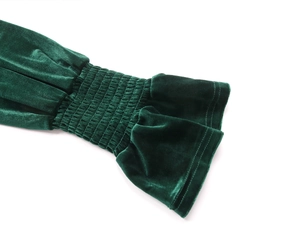 Close-up of smocked velvet sleeve with elegant ruffle cuff in deep green fabric