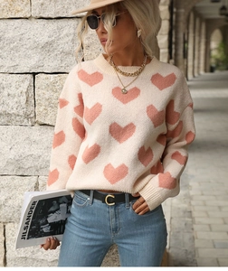 Outdoor street view of a sweet pink heart pattern sweater with blue denim jeans