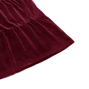 Close-up detail of burgundy velvet dress showing premium soft fabric texture and pleated hem