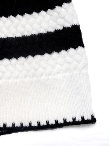 Detail of black and white striped knit sweater with diamond pattern and scalloped hem
