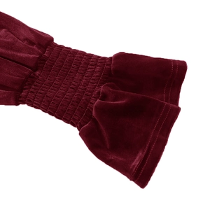 Detail of smocked velvet sleeve cuff with elegant ruffle design on a dark red dress