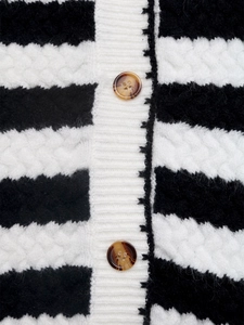 Detail view of black and white striped knit cardigan with cable pattern and amber buttons