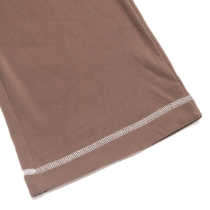 Detailansicht des braunen Strickstoffs mit weißen dekorativen Kontrastnähten am Saum