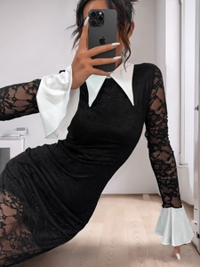Détail d'une robe en dentelle noire avec col blanc pointu et manches évasées transparentes